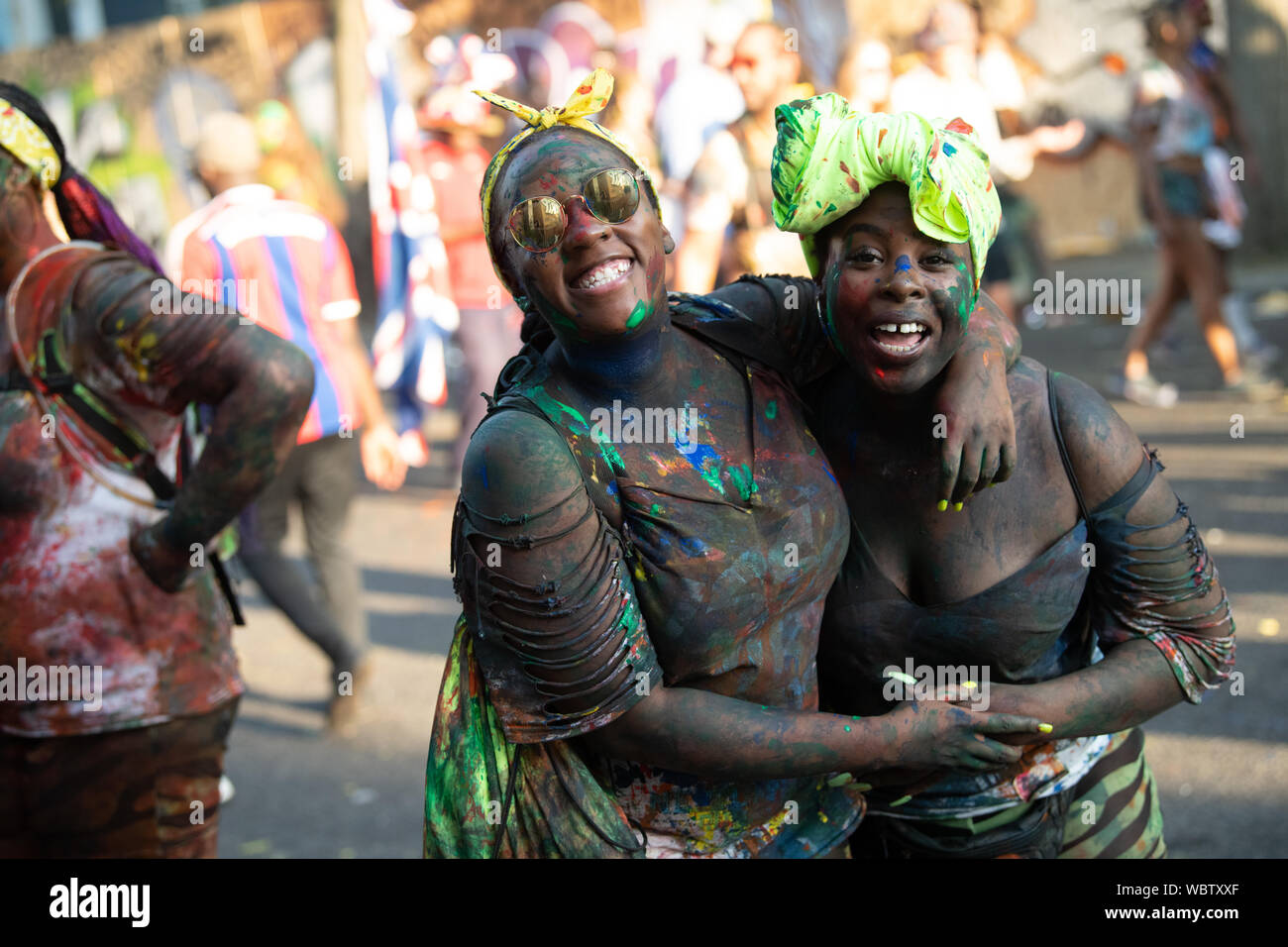 Un gruppo di donne al carnevale di Notting Hill dancing in una folla di persone coperte di vernice. Foto Stock