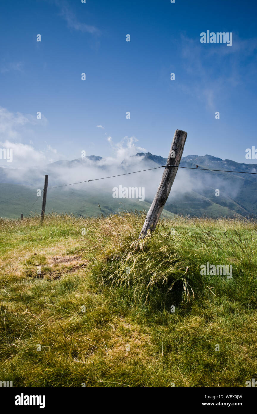 Un palo da recinzione alla sommità del Pic d'Estibat nei Pirenei francesi con la mattina presto le nuvole del sollevamento in background. Foto Stock
