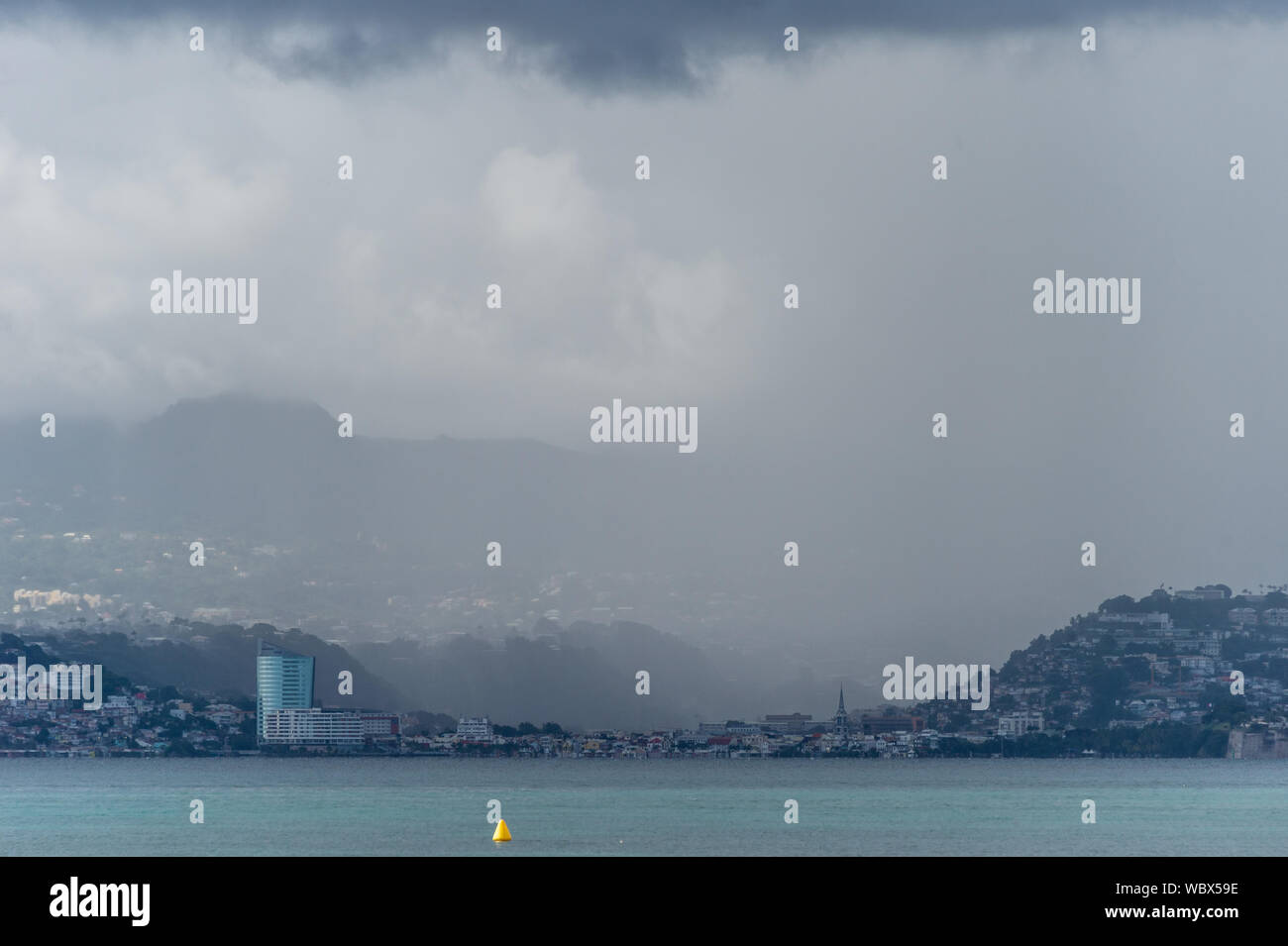 Trois-Ilets, Martinica, FR - 22 agosto 2019: heavy rain oltre Fort-De-Francia e Montagne Pellee Vulcano. Foto Stock