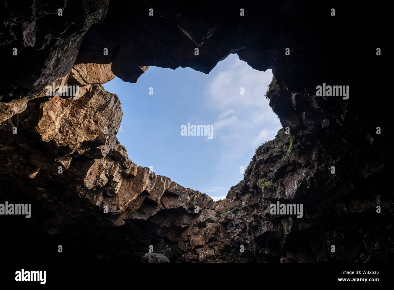 Volcanig entrata della caverna che mostra un cielo blu Foto Stock