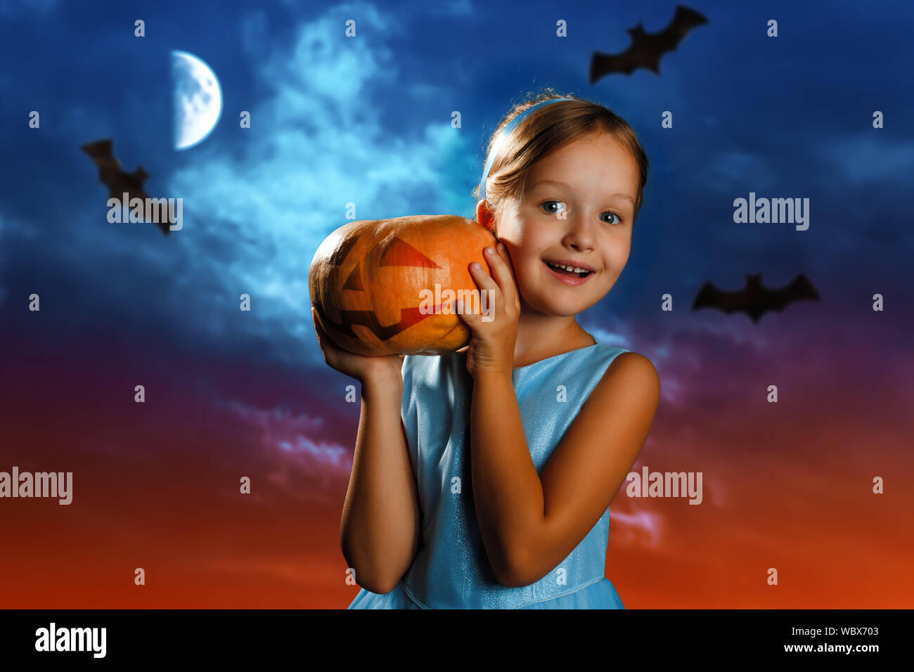 Carino bambina vestita come la principessa Cenerentola è in possesso di una zucca contro lo sfondo della sera cielo della luna. Festa di Halloween. Foto Stock