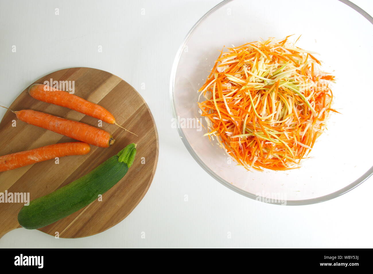 Direttamente sopra il colpo di carota e zucca sul tagliere di legno. Verdure grattugiato nella vaschetta trasparente Foto Stock
