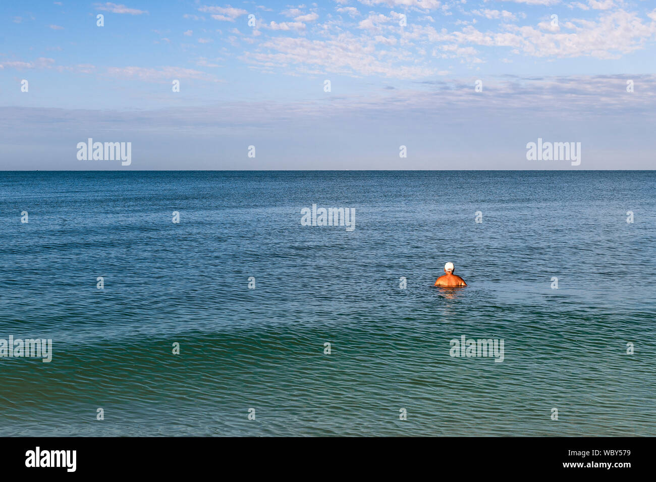 Senior uomo nuotare nell'oceano e visualizzazione di orizzonte, spiaggia a piedi nudi Foto Stock