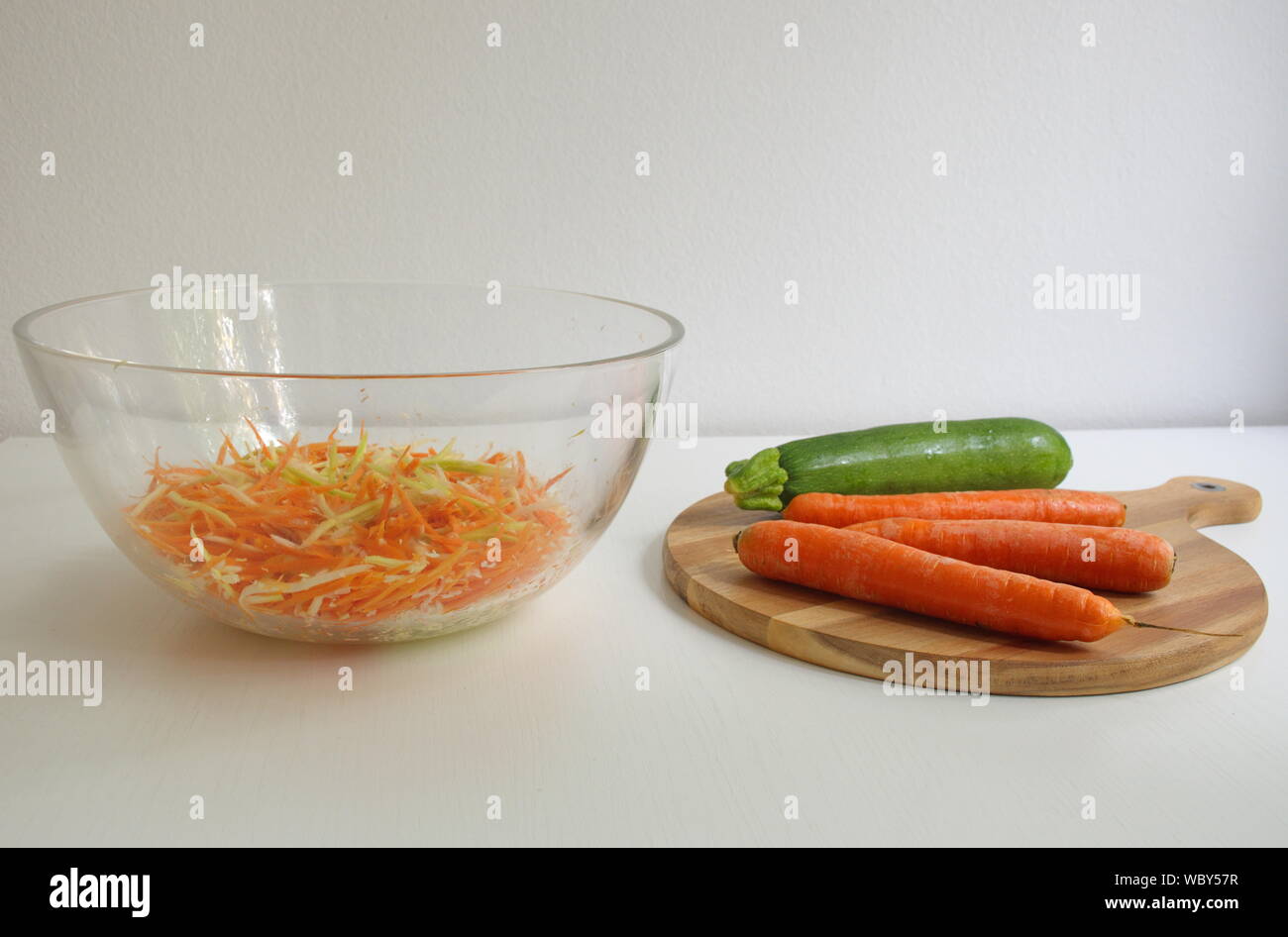 La carota e la zucca sul tagliere di legno. Verdure grattugiato nella vaschetta trasparente Foto Stock