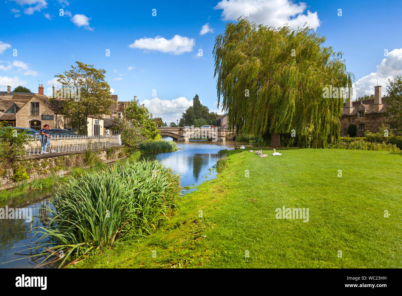 Il fiume Welland presso i prati dalla città ponte, Stamford Lincs. Regno Unito, sole luminoso con due turisti godendo della vista Foto Stock