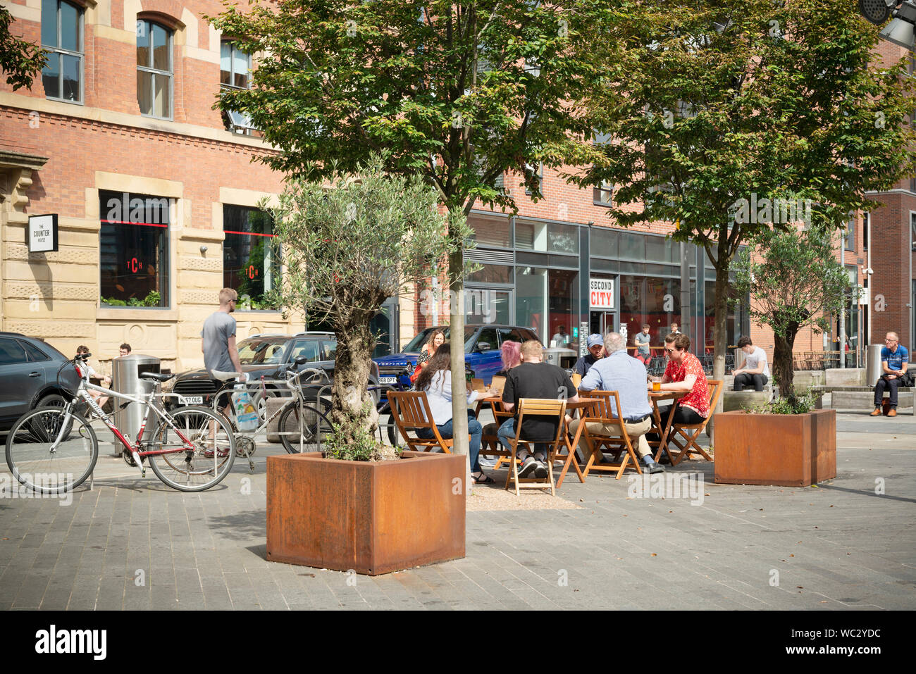 Le persone godono di sole in una piccola piazza tra la cappa Street, Blossom Street e cotone Street in Ancoats, Manchester, Regno Unito. Foto Stock