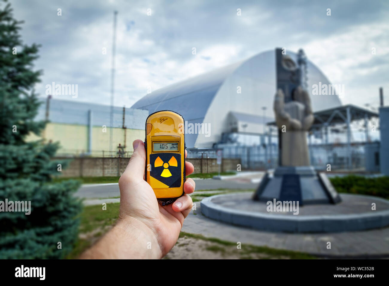 Un dosimetro in mani con un livello di radioattività vicino al monumento al Chernobyl liquidatori in prossimità del quarto reattore. Disastro di Chernobyl storia. L Foto Stock