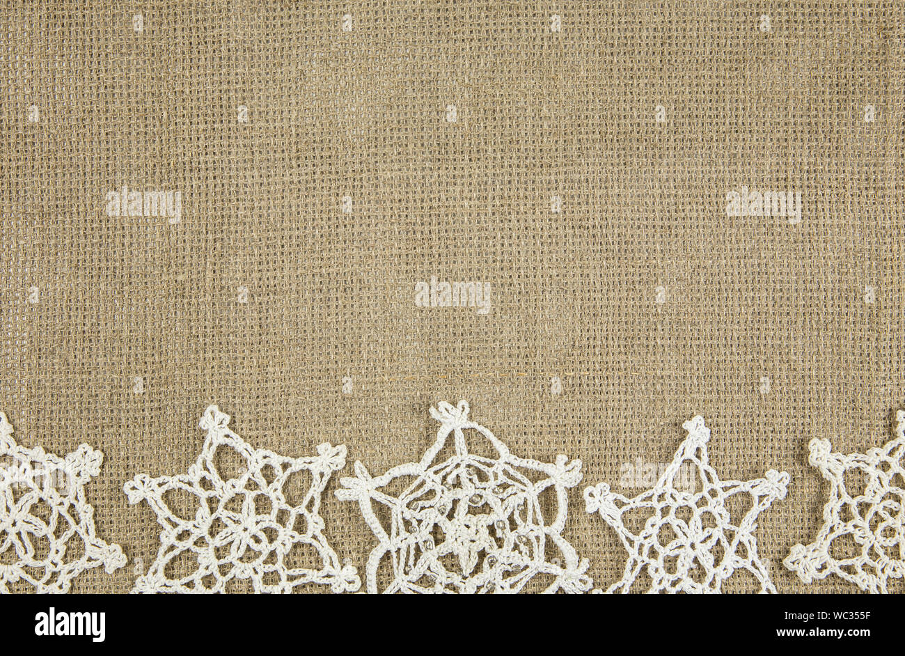 Marrone minimalista di ricamo in tessuto di cotone con fiocchi di neve a crochet. Vintage confine Natale concetto di frame. Foto Stock