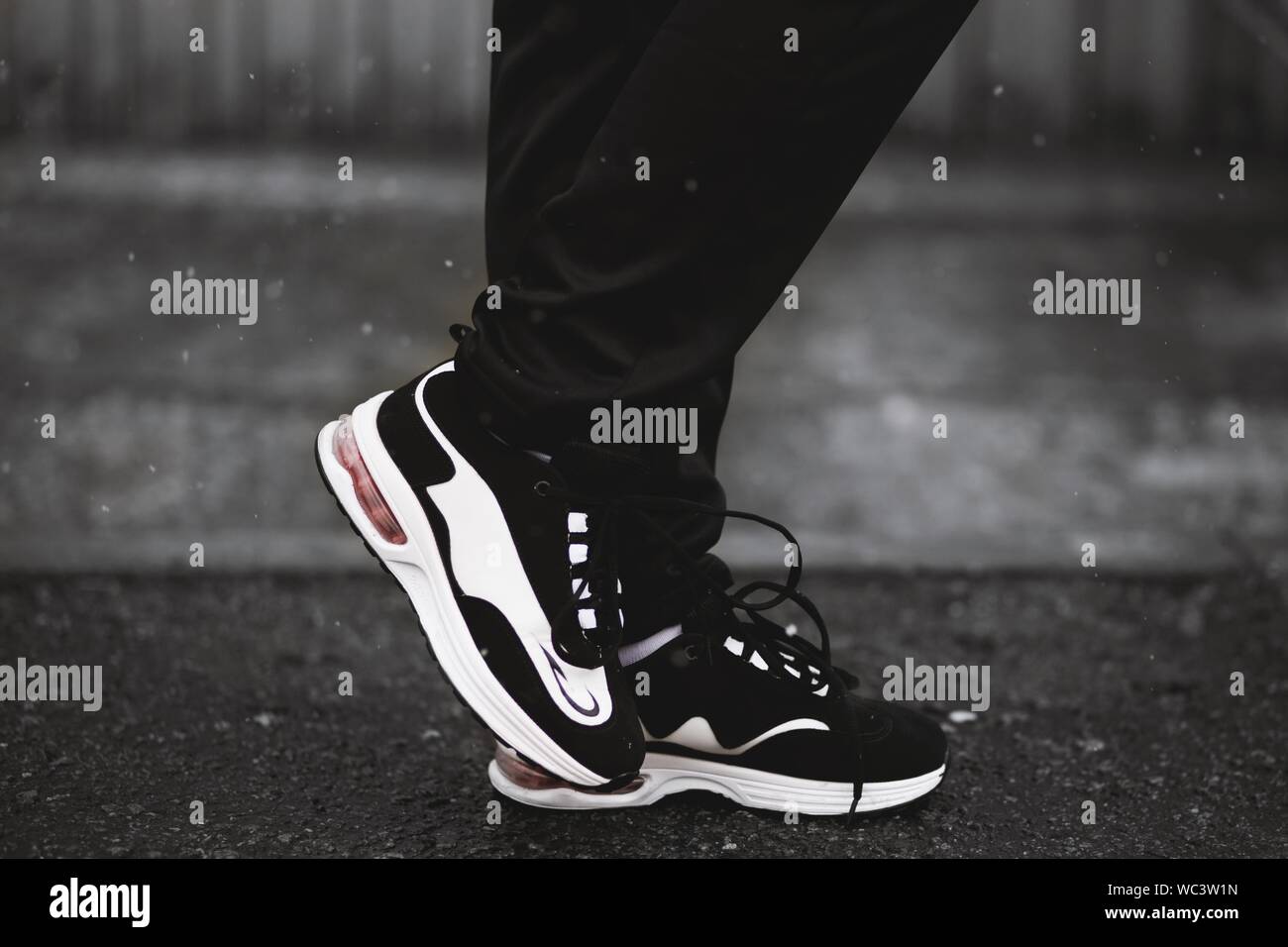 Primo piano verticale selettivo di una persona che indossa nero e. sneaker bianche Foto Stock