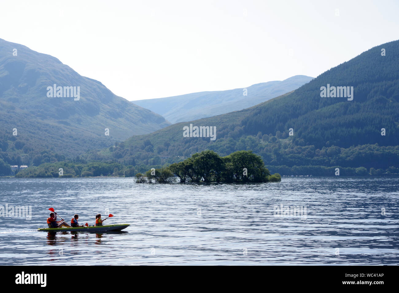 Canoa passando una delle molte isole sul Loch Lomond a Rowardennan Foto Stock