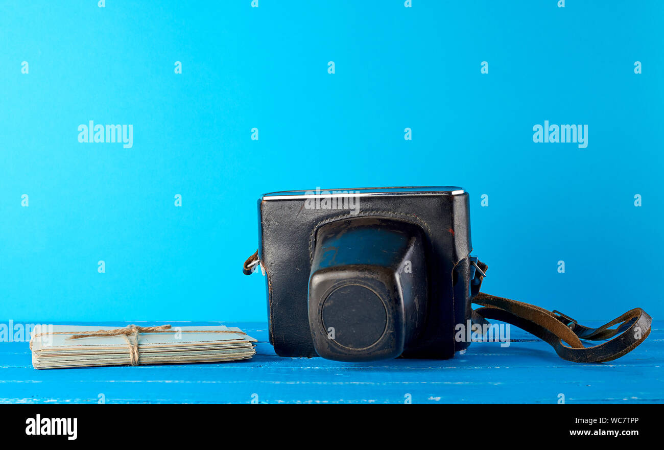 Vecchia fotocamera a pellicola in un marrone custodia in pelle su uno sfondo blu e corda legato cartoline vintage Foto Stock