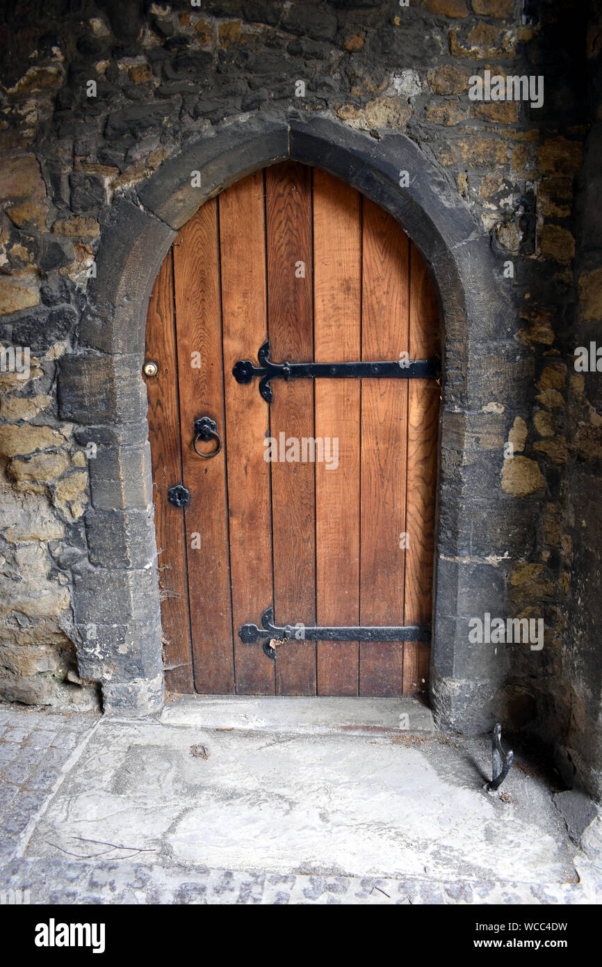 Una vecchia porta di legno insieme in una cornice di pietra con una lottatrice di avvio Foto Stock