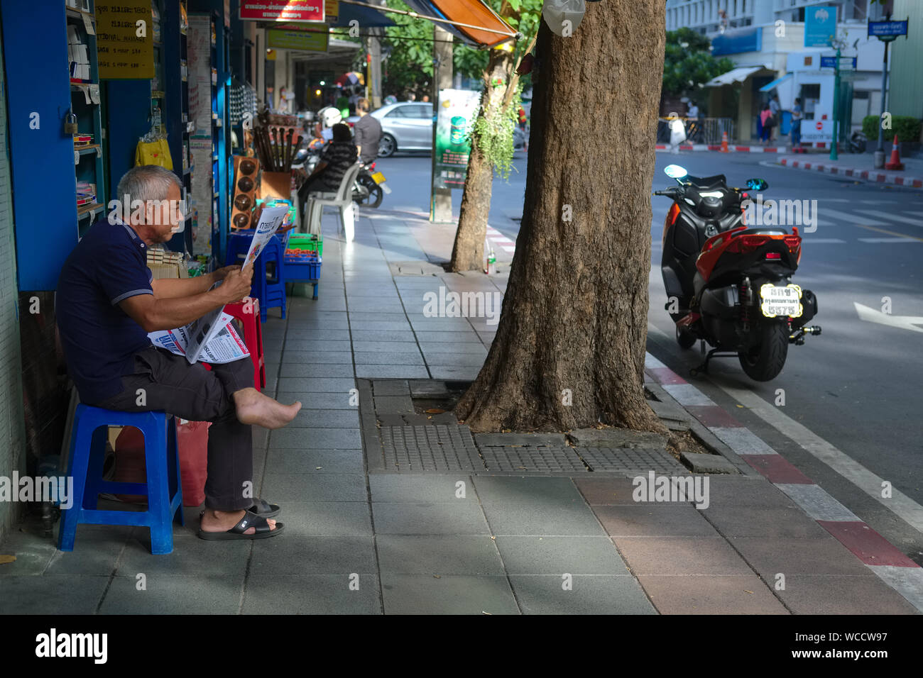 Uno della diminuzione del numero di lettori di giornali in Thailandia, seduto di fronte al suo negozio nell'area della città vecchia di Bangkok, Thailandia Foto Stock