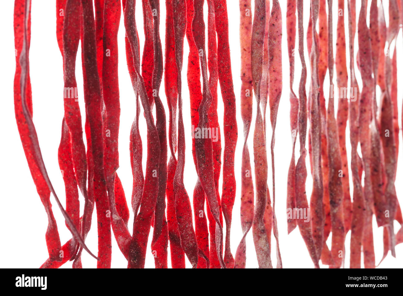 Freschi Fatti in casa pasta di barbabietole processo di essiccazione. Raw pasta di colore rosso su sfondo bianco. Foto Stock