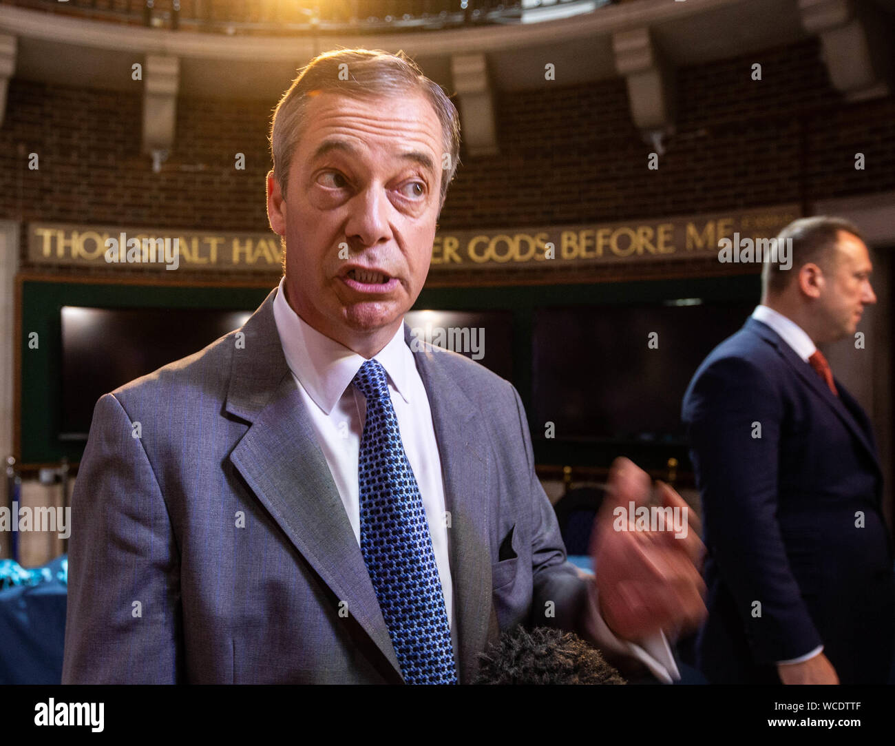 Brexit leader del partito, Nigel Farage, dà una pressa intervista con uno dei dieci comandamenti " Non avrai altri dèi di fronte a me' sulla parete in t Foto Stock