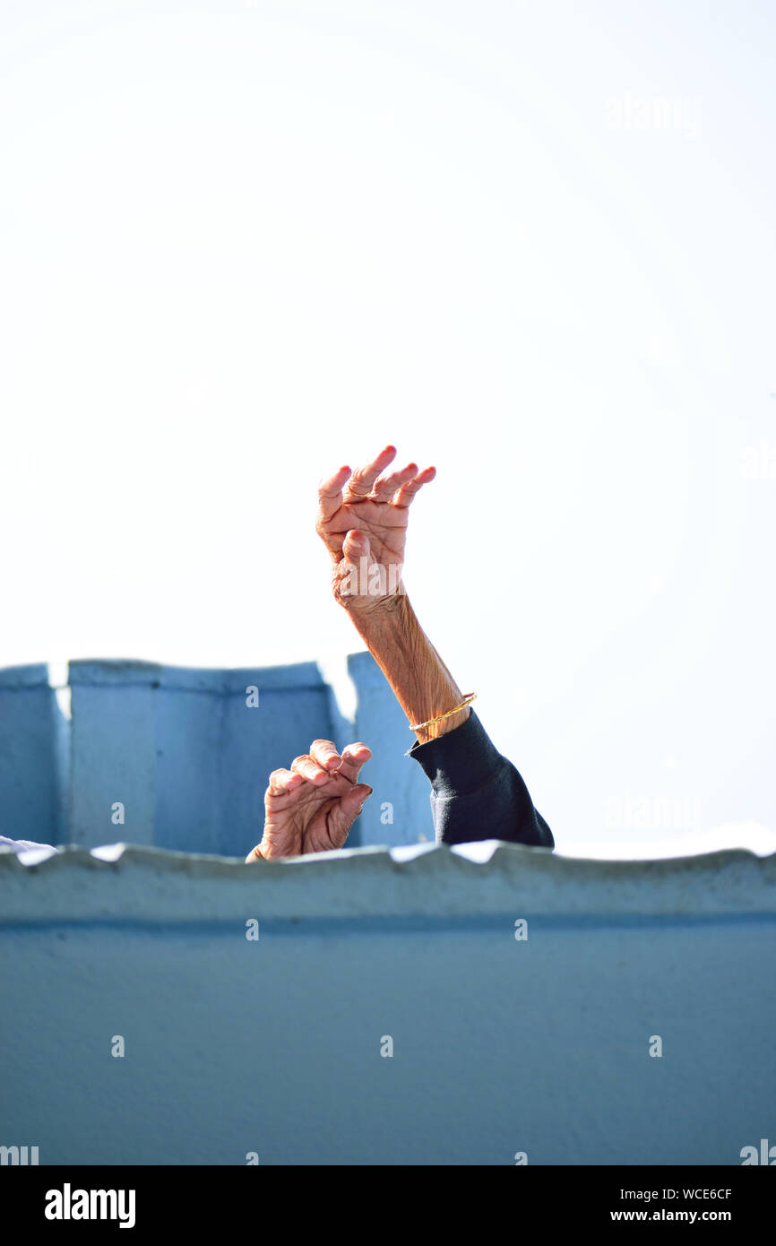 Una vecchia donna ha sollevato il suo stropicciato le mani verso il cielo. Foto Stock