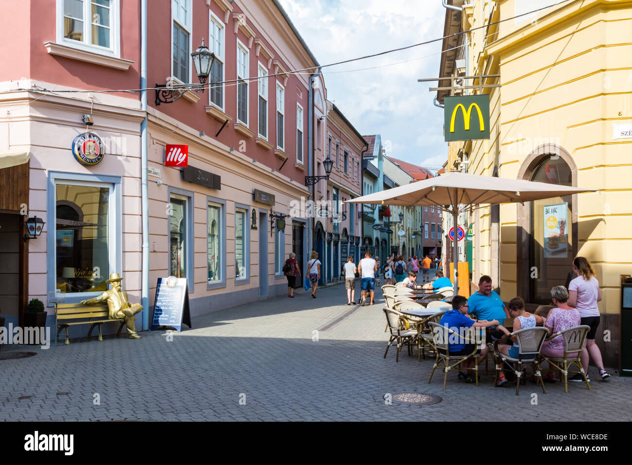 Szent Janos utca isola pedonale a Eger, in Ungheria con la gente seduta al tavolo esterno del McDonalds Foto Stock