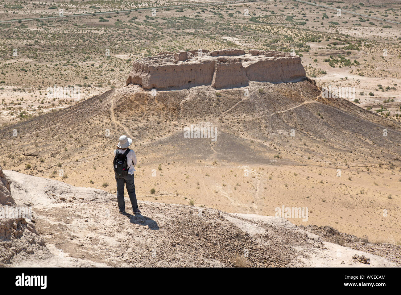 Turista femminile guardando oltre la Ayaz Kala Fort, Uzbekistan. Situato su una collina con vista sul deserto Kyzylkum. Costruito nel II secolo D.C.. Foto Stock