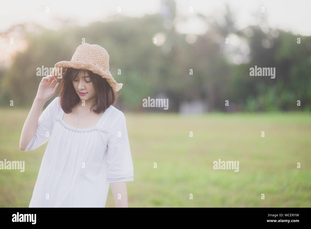 Donna che indossa cappello per il sole mentre si sta in piedi sul campo Foto Stock