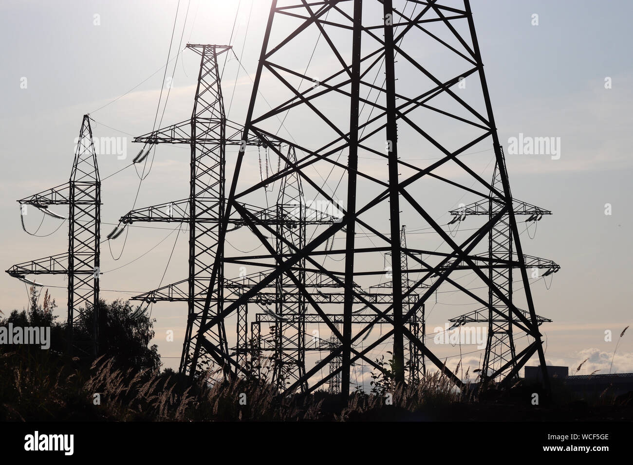 Impianto di alimentazione, linee di trasmissione di energia elettrica. Sagome di alta tensione torri con fili elettrici su sfondo al tramonto Foto Stock
