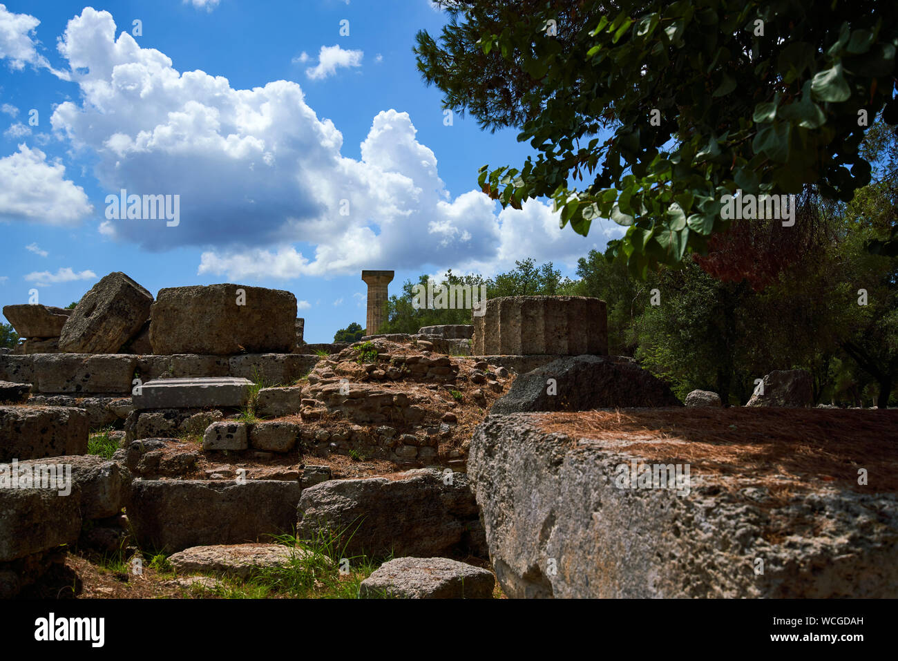 Resti del Tempio di Zeus ad Olimpia con una singola colonna ricostruita e disseminati in pezzi di colonna che circonda lo zoccolo Foto Stock