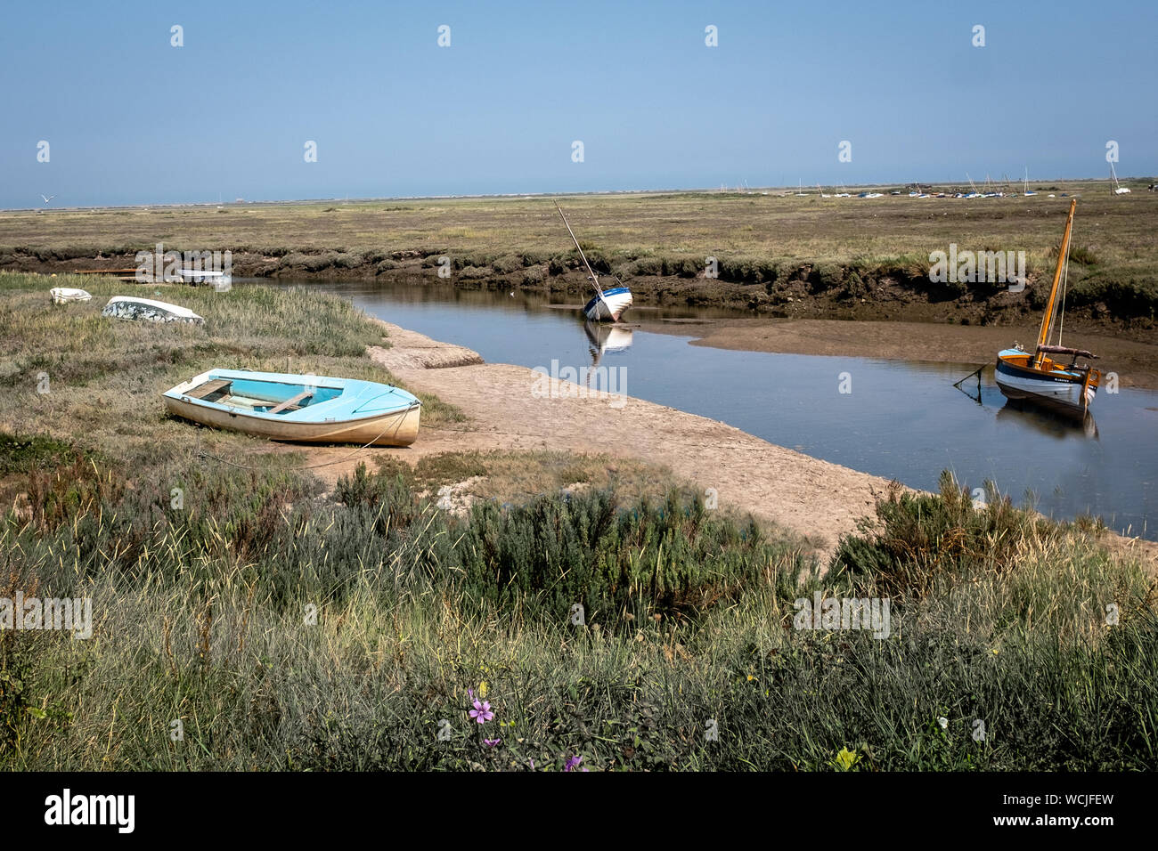 Piccolo Blu barca ormeggiata sulla terra asciutta da fiume Glaven, Blakeney, Norfolk Foto Stock