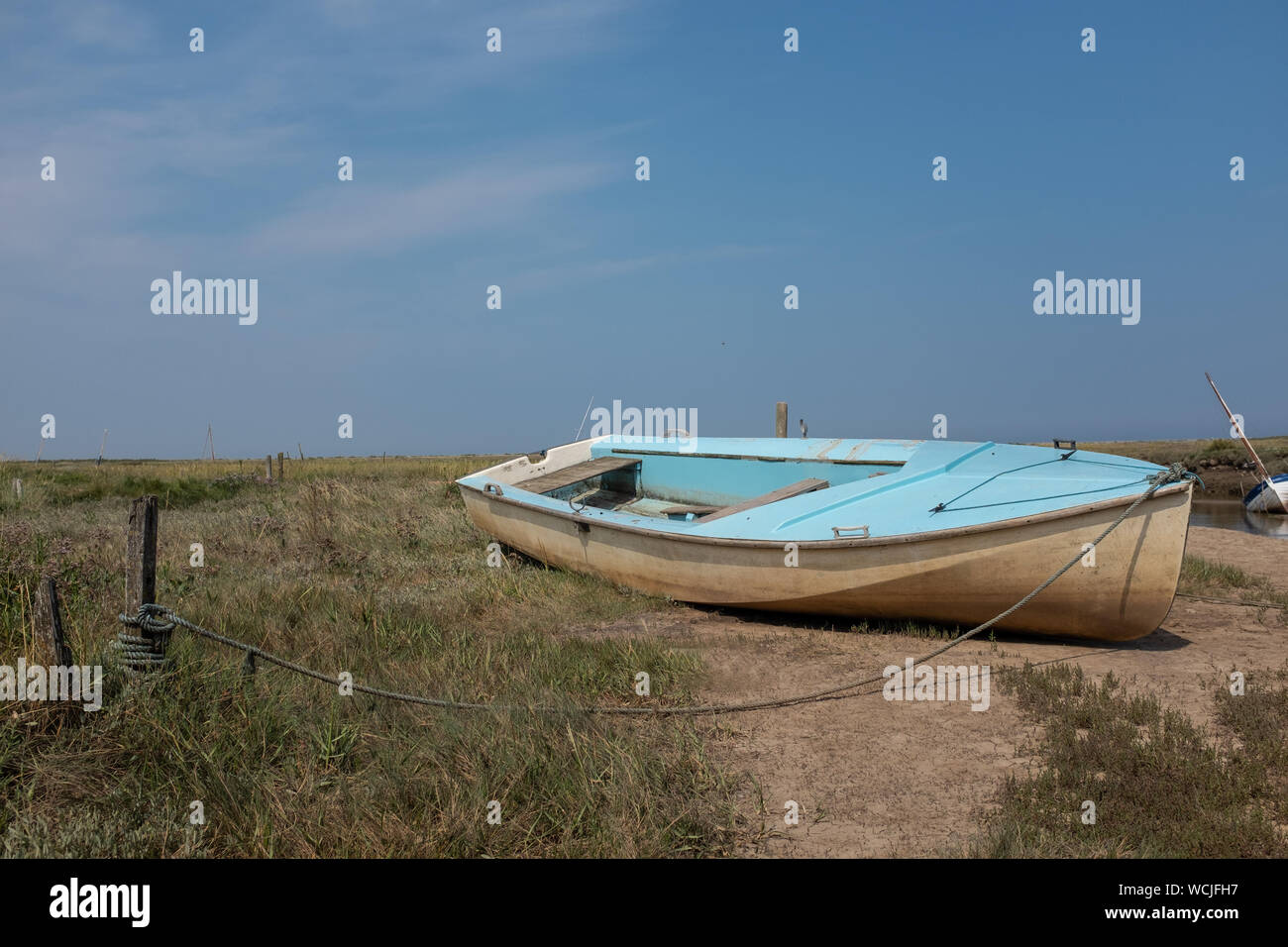 Little blue barca ormeggiata accanto al fiume Glaven a Blakeney, Norfolk, Regno Unito Foto Stock