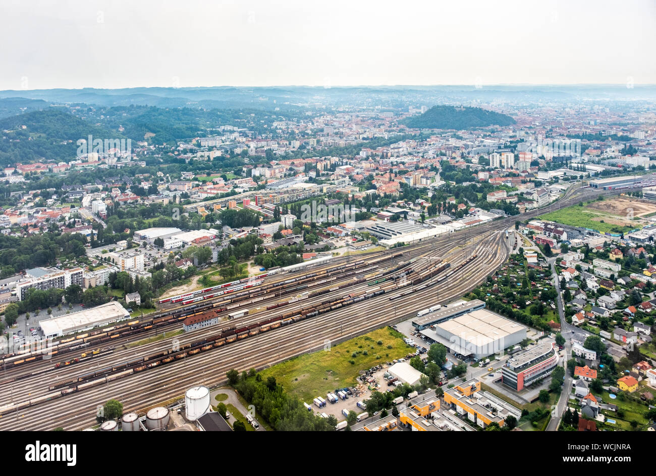 Vista aerea della città di Graz da elicottero drone con il distretto Gösting e la stazione ferroviaria in un nebbioso giorno di estate in Austria, Europa Foto Stock
