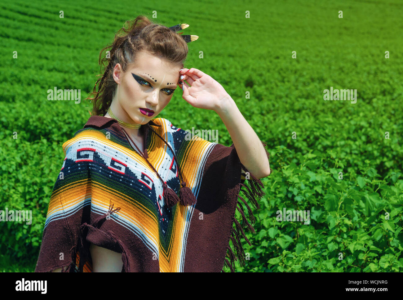 Ritratto di una ragazza con il trucco Amazon, Viking, guerra aggressiva di  vernice. Vestito in un poncho sullo sfondo del cielo, campo verde Foto  stock - Alamy