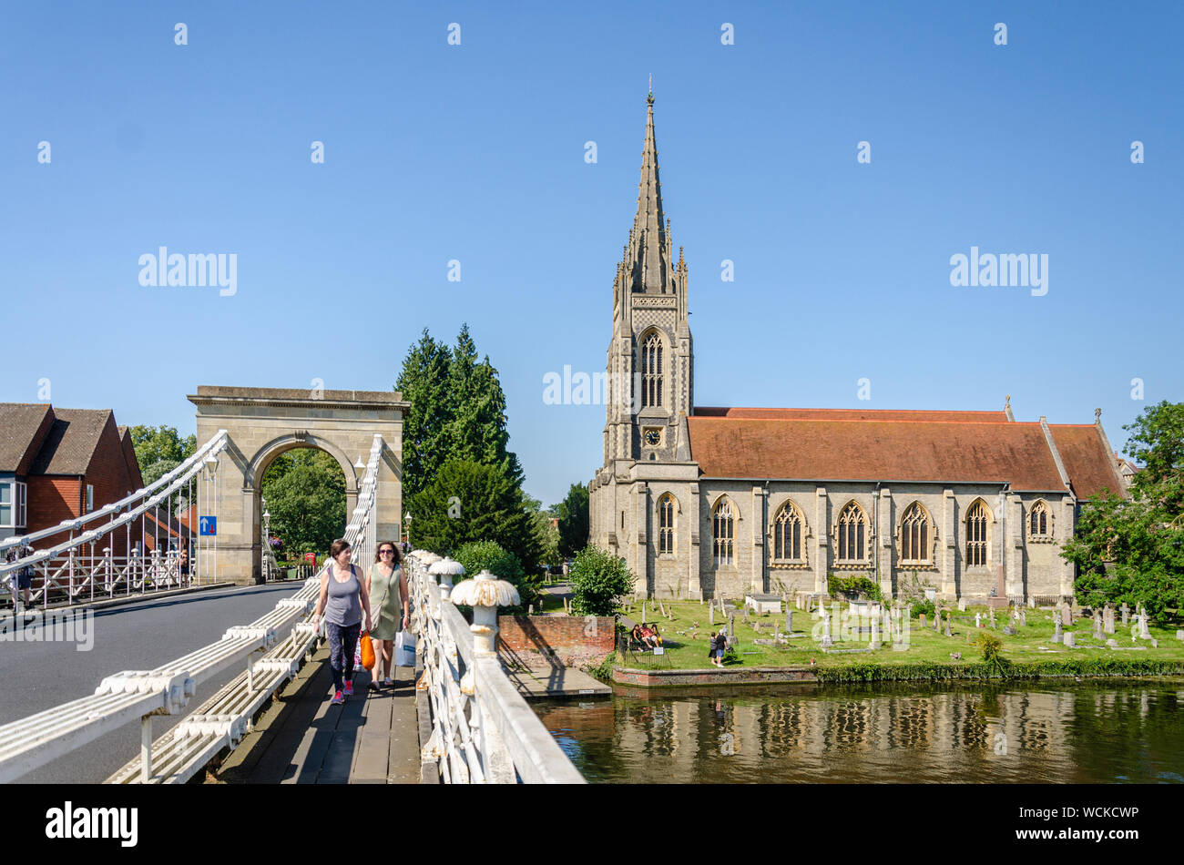 Marlow Bridge è una sospensione ponte che attraversa il fiume Tamigi a Marlow, Buckinghamshire, UK. Al di là di essa è Chiesa di Tutti i Santi di Marlow. Foto Stock