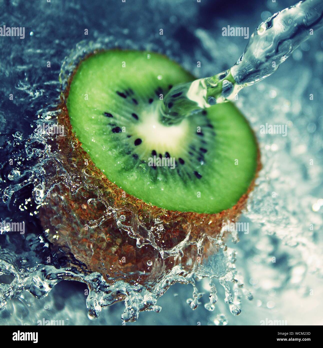 Una succosa di kiwi freschi tagliati a fettine a metà in un acqua splash Foto Stock
