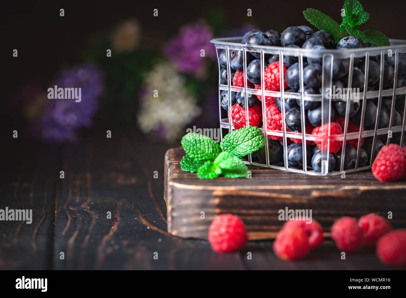 Il lampone e mirtillo in un cesto su uno sfondo scuro. Estate e cibo sano concetto. Sfondo con copia spazio. Messa a fuoco selettiva. Orizzontale. Foto Stock