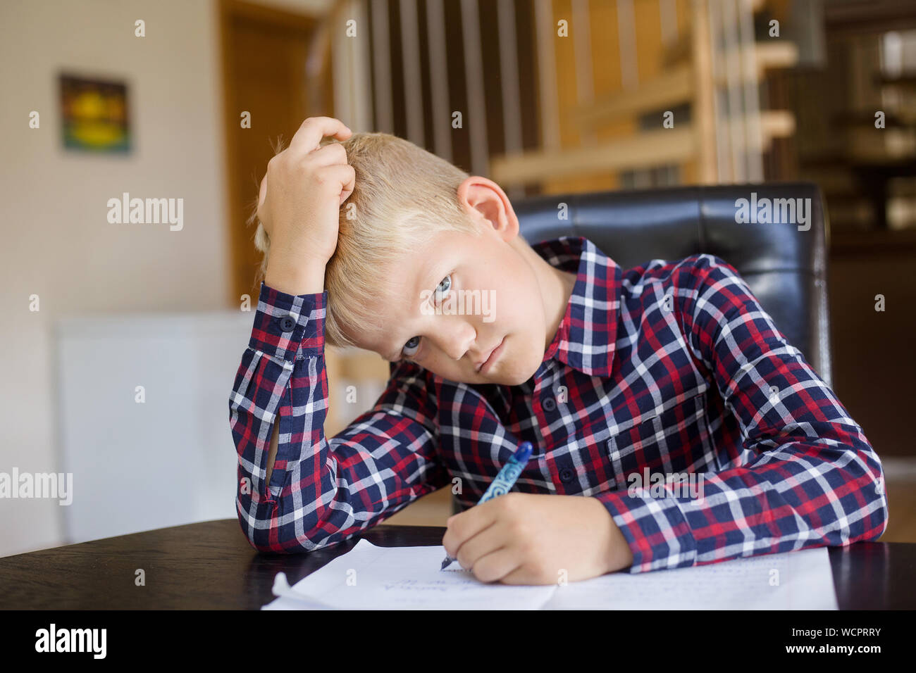 Triste schoolboy iscritto al notebook a casa. Compiti a casa. Istruzione, infanzia e concetto di persone Foto Stock