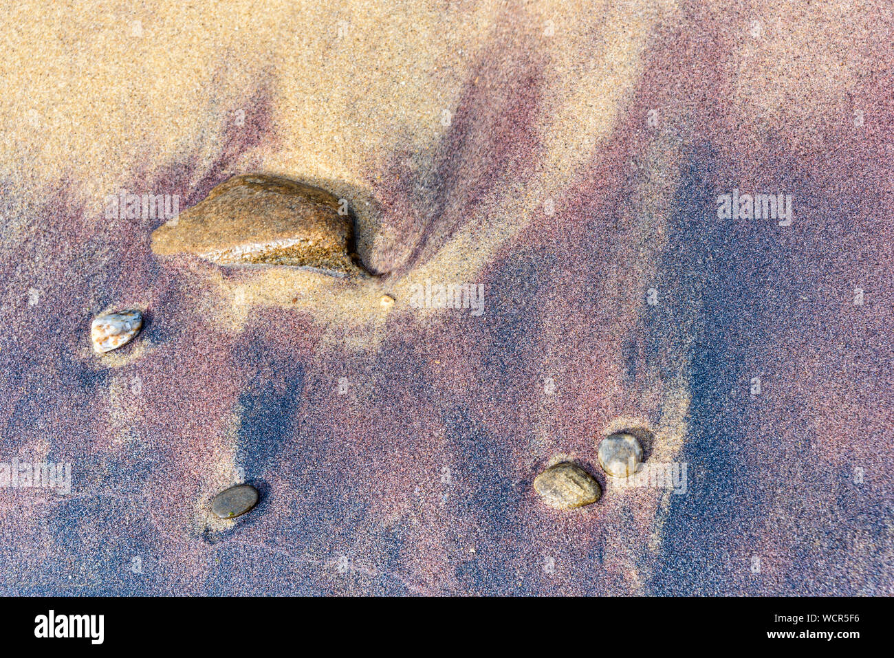 Spiaggia di rosso e di giallo sabbia e pietre di mare Foto Stock