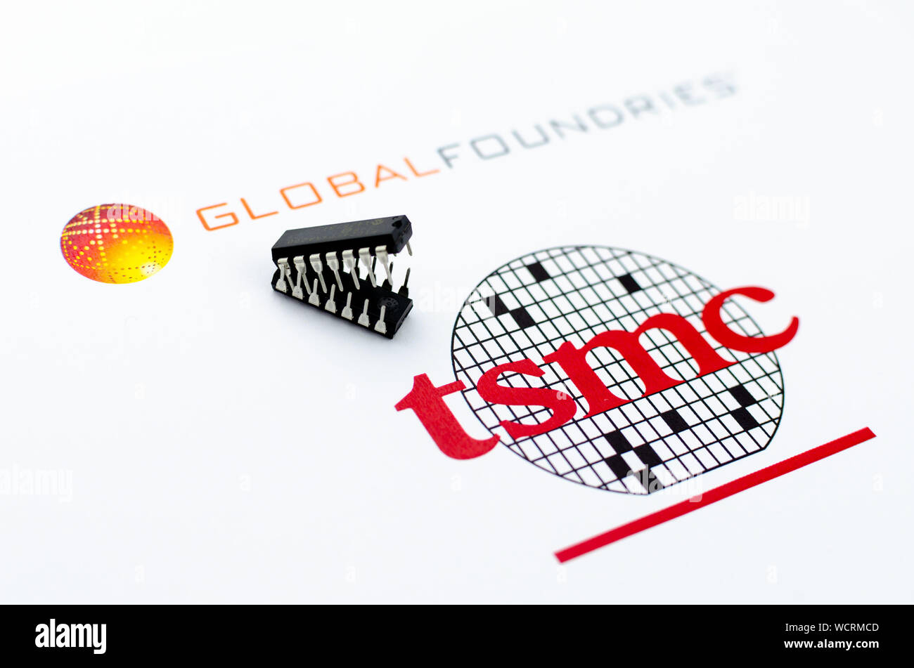 Fonderie globale vs. TSMC. Loghi stampati di aziende di semiconduttori e due microchip in forma di attaccare le ganasce. Foto concettuale. Foto Stock