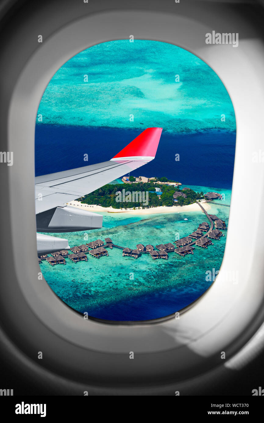 Vista attraverso la finestra aereo sul volo aereo ala fronte isola tropicale nell'oceano indiano maldive. trasporto vacanza viaggi aerei di volare conc Foto Stock