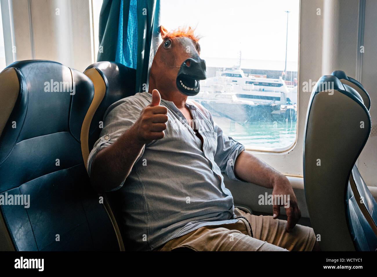 Cavallo-uomo è pronto per andare in vacanza. Egli siede inide il traghetto con il pollice verso l'alto. Crazy Holiday e il concetto di tempo libero Foto Stock