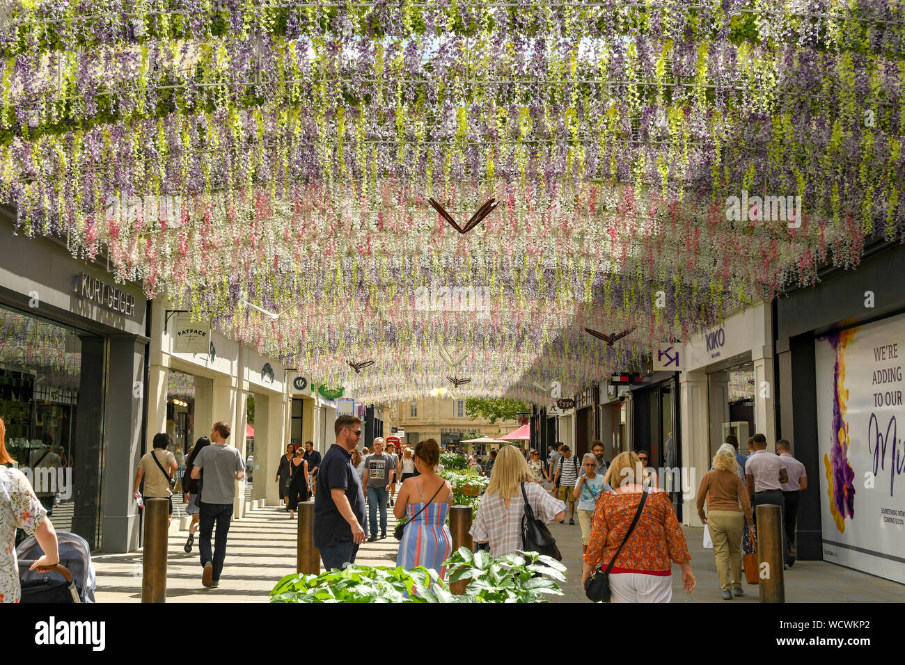 Bagno, Inghilterra - Luglio 2019: stringhe di fiori artificiali che servono come una pantina parasole su una delle strade nel centro di Bath. Foto Stock