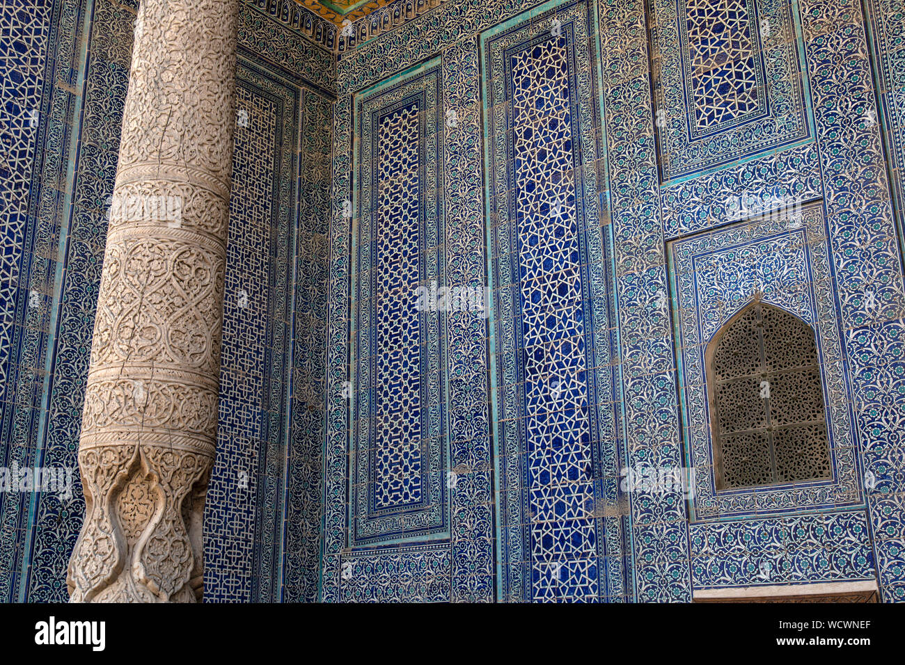 Dettagli di legno scolpito pilastri e il blu di piastrelle a mosaico in una moschea nella città di Khiva in Uzbekistan. Foto Stock