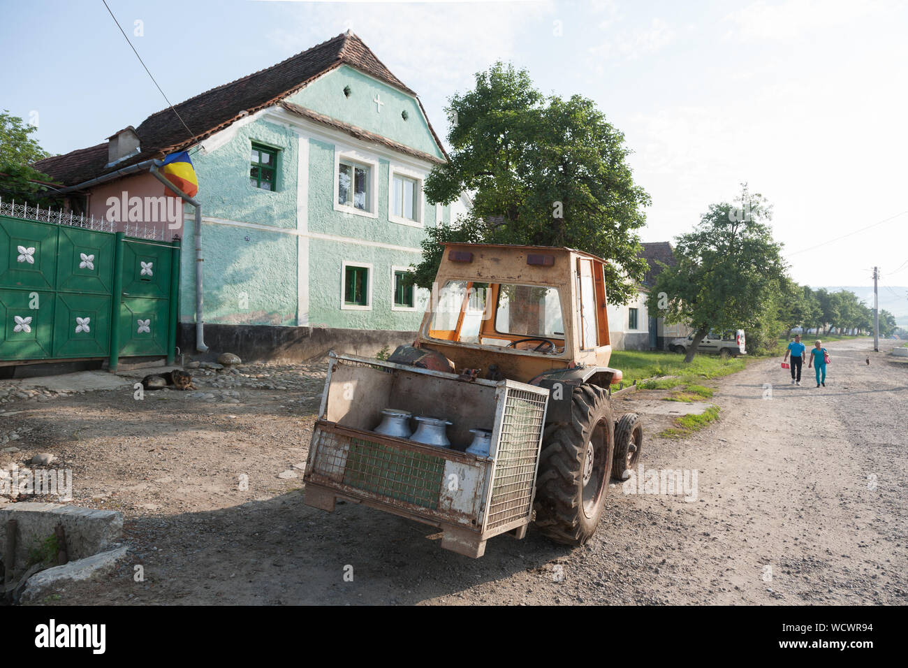 Un trattore che trasportano bidoni per il latte parcheggiato sulla strada principale nel villaggio di Viscri, Transilvania, Romania Foto Stock