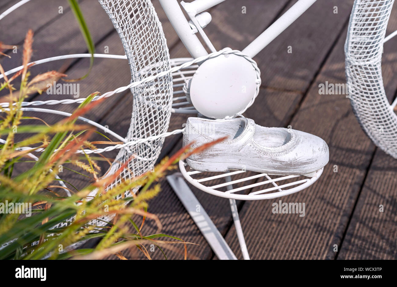 Per bambini sandali di metallo sono sul pedale della concept bike. Arredamento da giardino in forma di bambini sandalo in metallo. Foto Stock