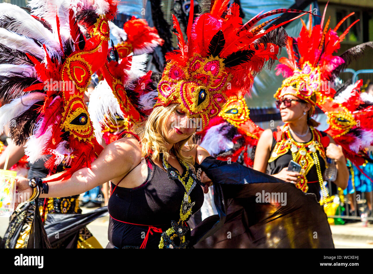 26 Agosto 2019 - donna in costume e copricapo dancing in parata, carnevale di Notting Hill su un caldo lunedì festivo, London, Regno Unito Foto Stock