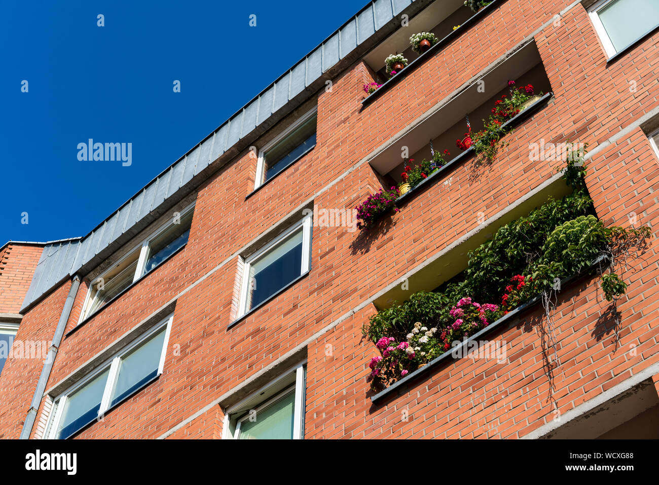 Klaipeda, Lituania - 28 Luglio 2019: residenziale Tradizionale mattoni rossi edificio con fiori in balconi Foto Stock