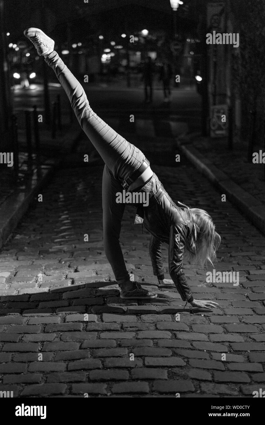Parigi, Francia - luglio 2, 2017: giovane donna bionda sta facendo ginnastica in notturna su strada nel centro della città di Parigi, in bianco e nero Foto Stock