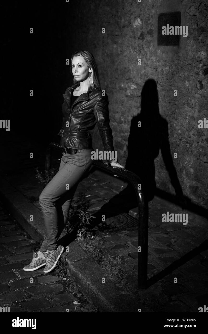 Parigi, Francia - luglio 2, 2017: giovane donna bionda in piedi da soli di notte sulla strada nel centro della città di Parigi, in bianco e nero Foto Stock