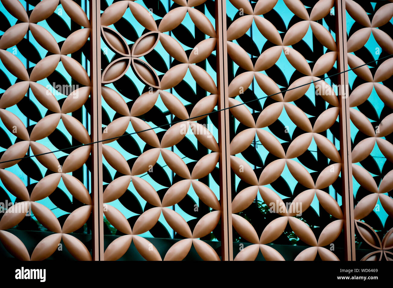 Ravvicinata di un rivestimento metallico su blu edificio di vetro esterno con motivi floreali di ripetizione dei motivi geometrici e di forte dettaglio come sfondo astratto Foto Stock