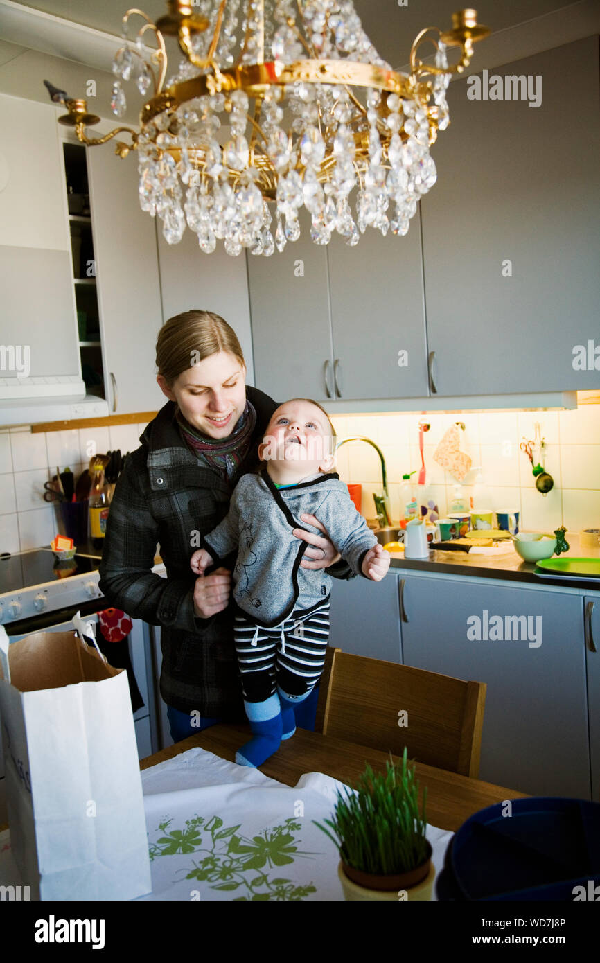 La madre e il bambino (6-11 mesi) in cucina domestica Foto Stock