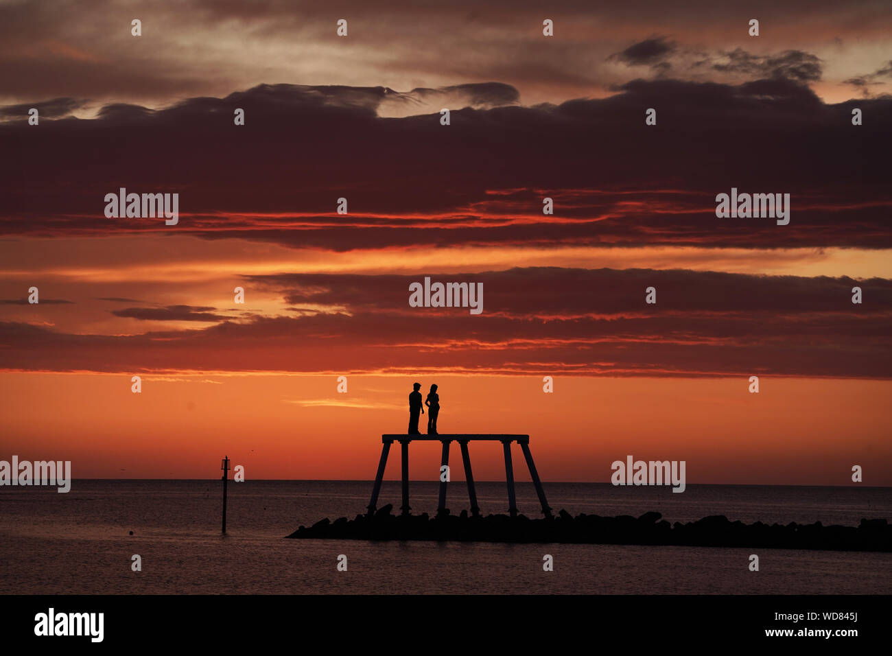 Il sole sorge sulla scultura " La Coppia " da artista Sean Henry, a Newbiggin-per-il-mare in Northumberland. Foto Stock