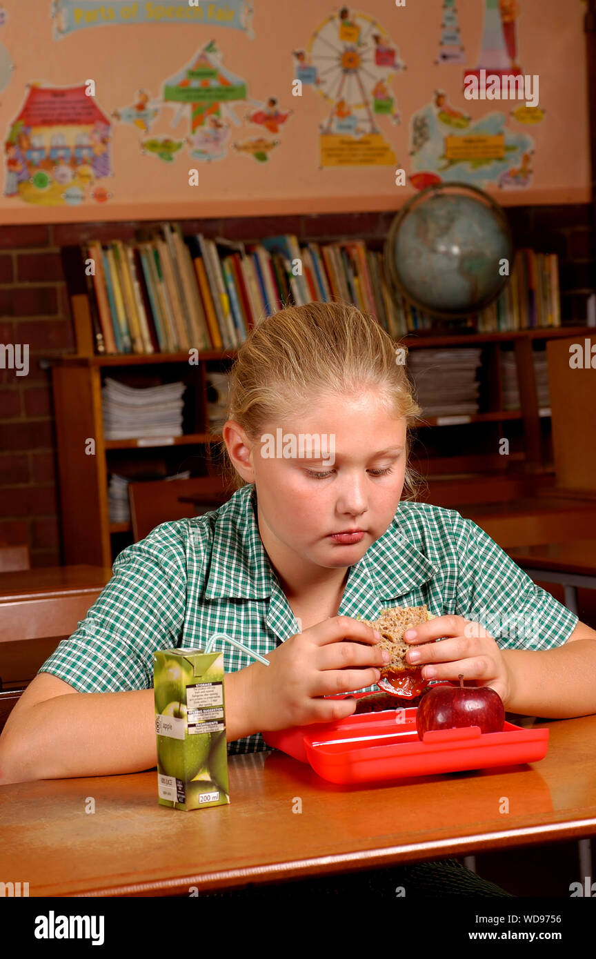 Un bambino di mangiare la sua salute il pranzo sul suo proprio come lei lotte con i ragazzi bulling lei. Foto Stock