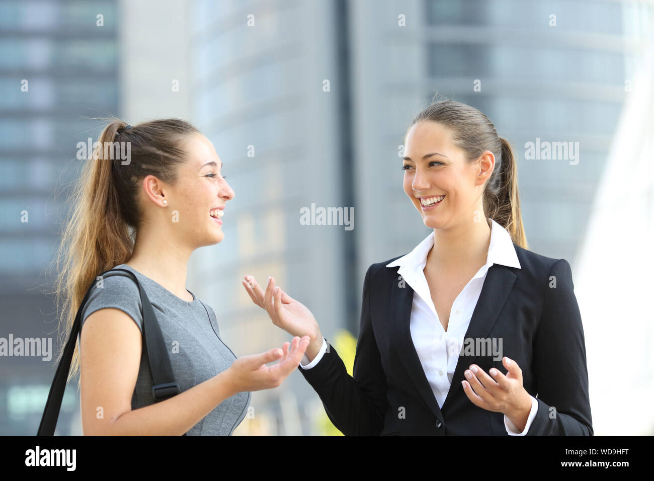 Due dipendenti in sede a parlare in piedi in strada con edifici per uffici in background Foto Stock